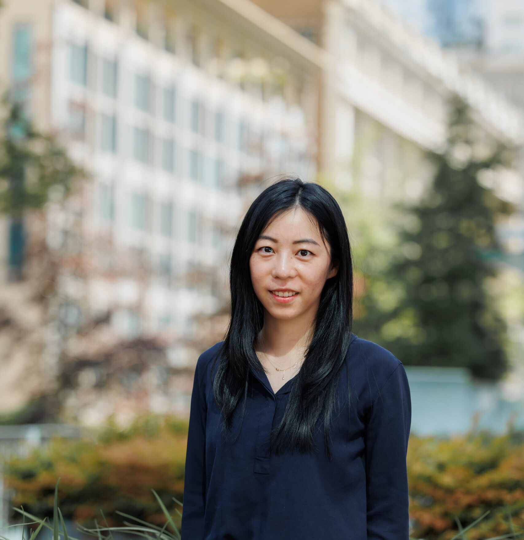 Alice standing in front of of blurred building.