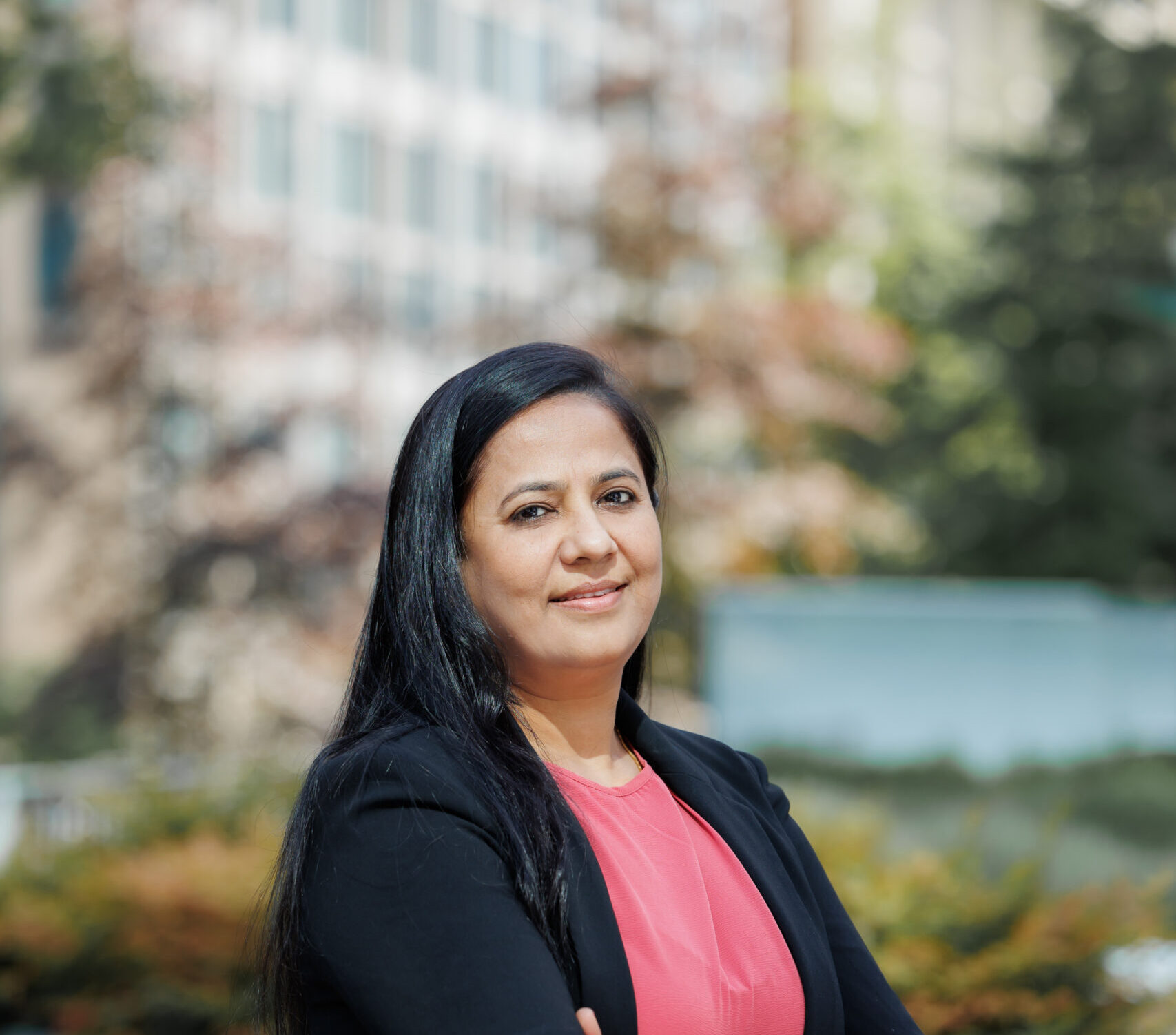 Tejal standing in front of a blurred green background with a building.