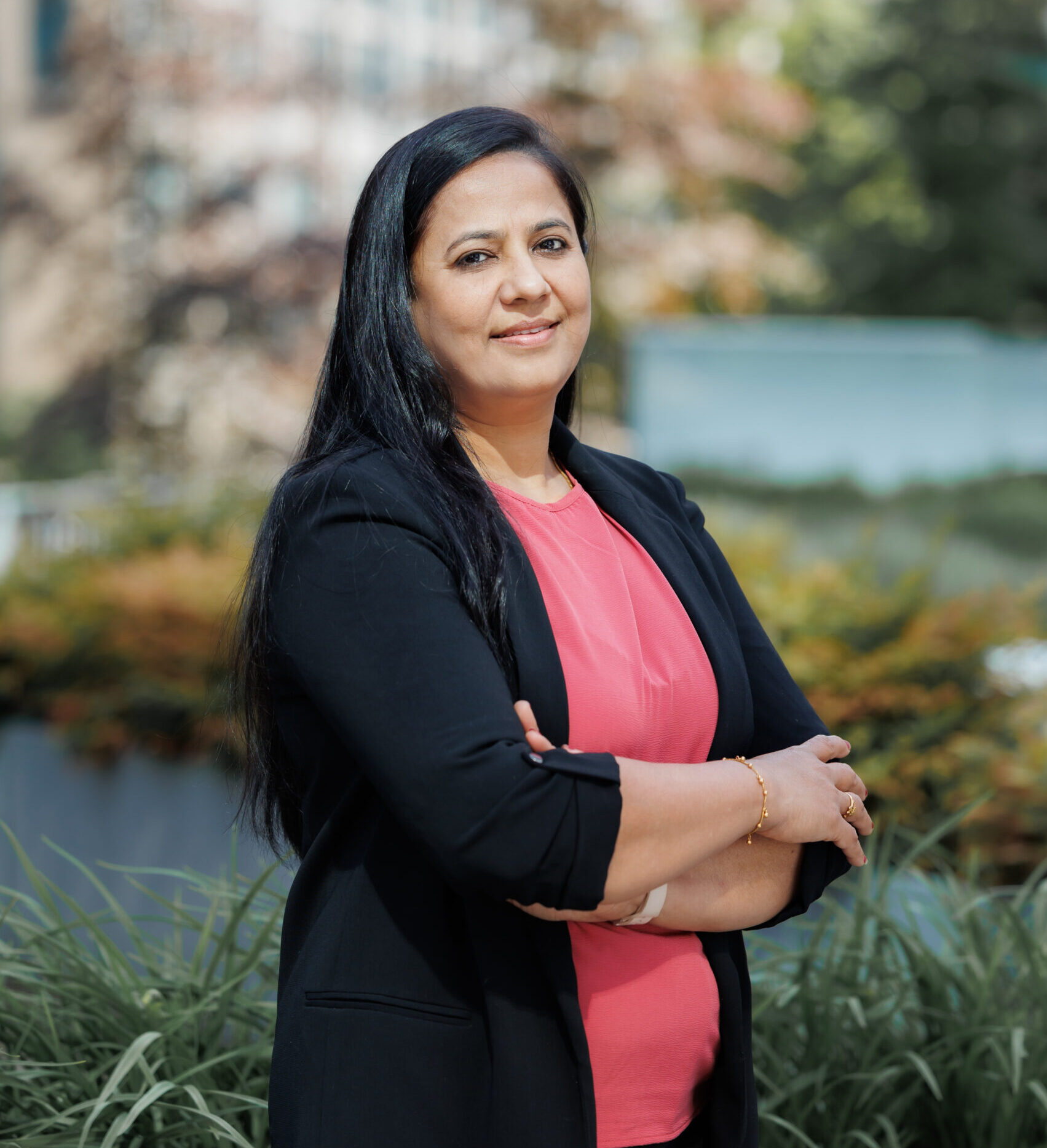 Tejal standing in front of a blurred green background with a building.