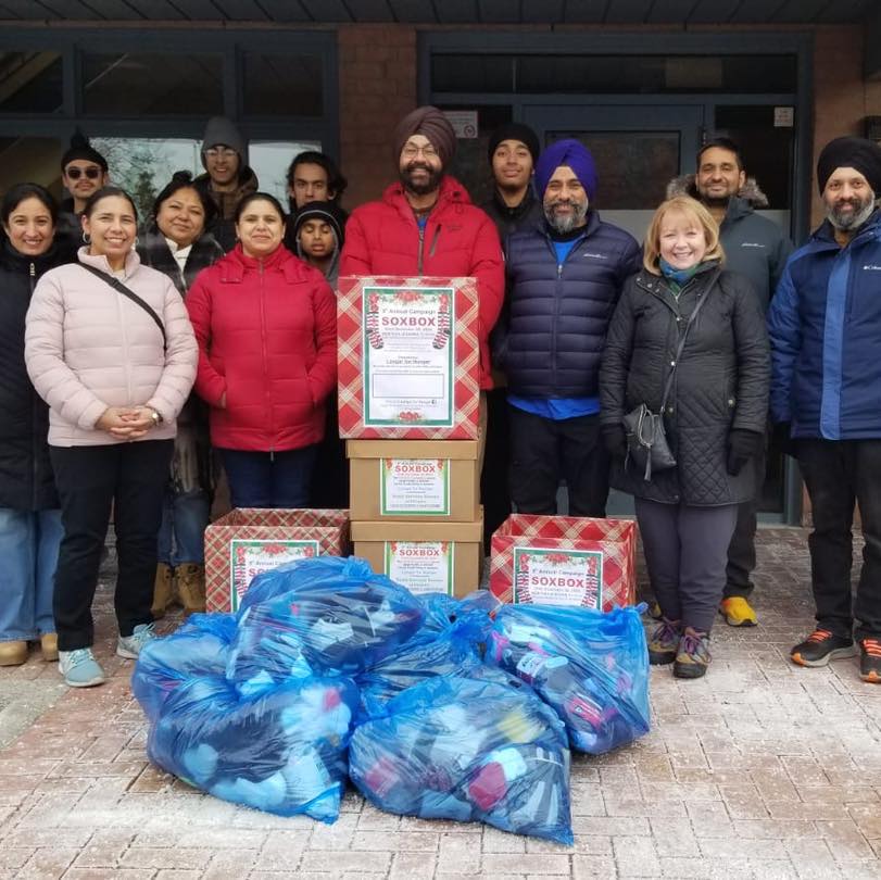 Group of people standing in front off bags of donated items.